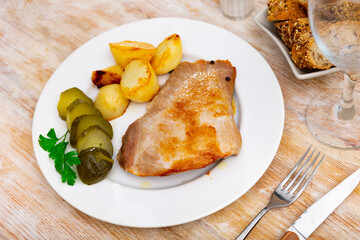 Delicious pork steak served with potatoes and pickles. Festive dinner
