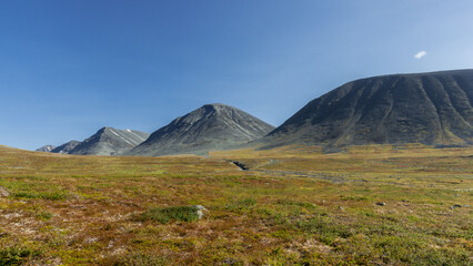 Breathtaking scenery to the mountain valley with dark steep mountains on horizon raising from...