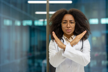 Confident African American woman doctor stands in modern office, expressing disapproval or concern...