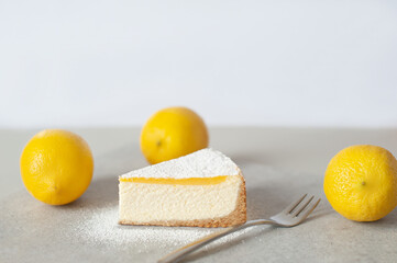 Sliced lemon cheesecake with fresh lemons beside it, showcasing a creamy texture and vibrant yellow color. Perfect dessert presentation.