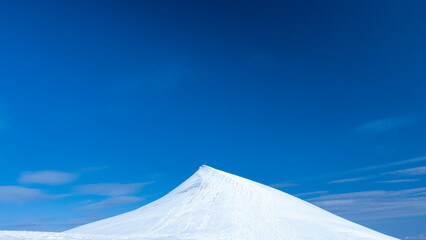 Beautiful minimal picture of snowy Kebnekaise peak contrasts with blue sky and some clouds during beautiful summer day in swedish Lapland nature