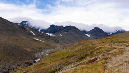 Nordic rocky nature with mountain glacier valley of Tarfala with breathtaking scenic view towards misty mountains and snow and highland grassy nature of swedish  Lapland landscape.