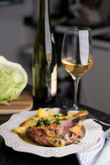 Roasted Duck Leg with Herbs and White Wine Gourmet Dining Experience. Succulent roasted duck leg seasoned with fresh herbs and paired with potatoes, served alongside a glass of white wine. 