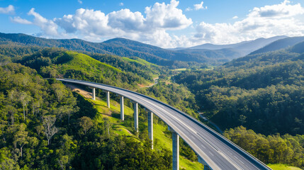 Fototapeta premium Modern Highway Bridge Over Lush Green Valley and Forested Hills