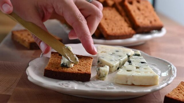 High-quality video of creamy Gorgonzola cheese being spread on traditional spicy French gingerbread with cinnamon. Perfect for showcasing gourmet cuisine, artisanal dairy products, 4k
