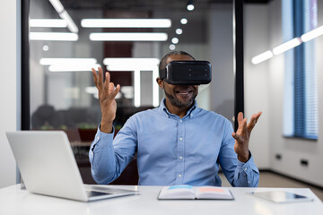 Mature african american businessman using virtual reality headset in office. Enthusiastically gesturing while exploring digital world. VR technology enhancing business creativity and strategy.
