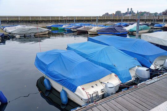 Boats and yachts covered with awnings and moored for wintering at the pier in a private port.