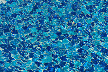 Glittering blue water ripples create a mesmerizing pattern on a sunny afternoon at the pool