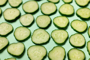 Slices of fresh cucumbers on turquoise background, above view