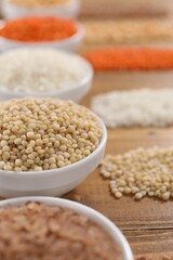 Different types of cereals and legumes on wooden table, closeup