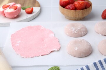 Tasty homemade mochi, dough and strawberries on table, closeup
