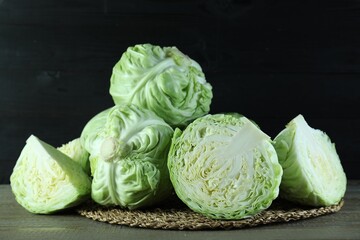 Whole and cut fresh cabbages on wooden table