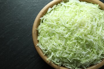 Fresh shredded cabbage on black table, top view