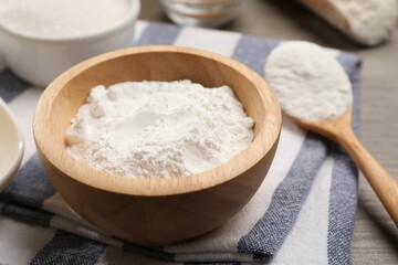 Baking powder in bowl on wooden table, closeup