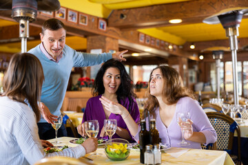 Smiling men invite women to dine for their table in the restaurant