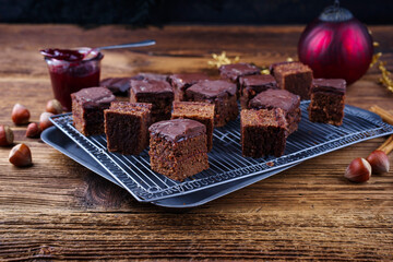 Homemade fudgy brownies domino cake pastry cubes with marmalade and dark chocolate topping glaze served as close-up on a cooling rack