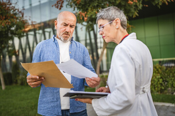 Senior policeman show evidence of the victim to mature doctor outdoor