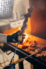 Close-up of skewered meat roasting over an open flame, capturing intense heat and flavor of grilling