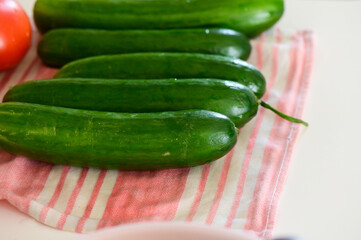 Fresh cucumbers arranged on a pink striped kitchen towel, ready for a delicious summer salad preparation
