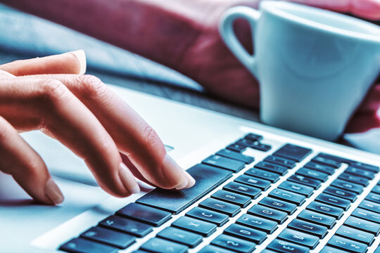 Typing hand with blurred coffee in background
