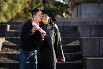 Transgender woman recent graduated, dressed in cap and gown, showing off his degree celebrating with her family