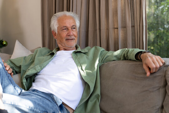 Relaxing on sofa, senior man enjoying peaceful afternoon at home
