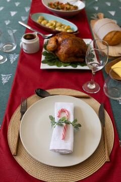 Festive Christmas table setting with roasted chicken and candy cane decor, at home