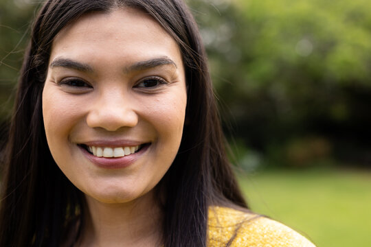 Smiling woman enjoying sunny day outdoors in green park setting, copy space