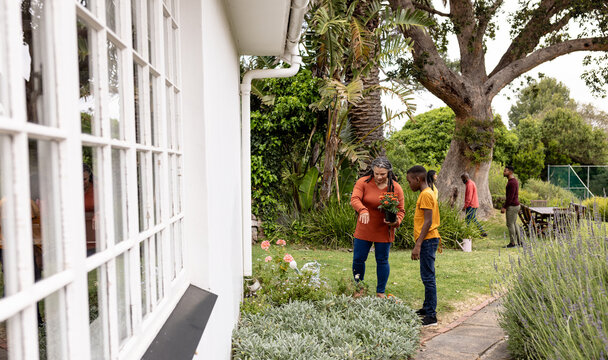 mutliracial family gardening together in backyard, sharing laughter and enjoying outdoor time