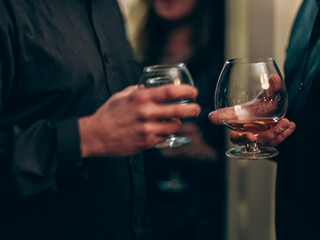 Two men holding cocktail glasses at a social party gathering