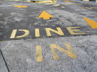 Dine In sign painted in yellow on a grey gray asphalt bitumen road