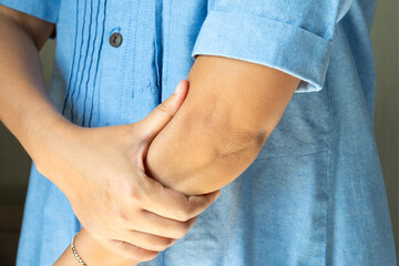 woman has pain in his elbow and tendon muscles and he relieves the pain with a massage. Health and...