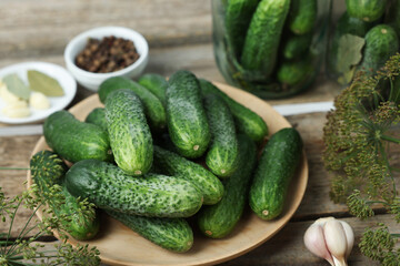 Fresh cucumbers, dill and spices on wooden table, closeup. Preparation for pickling