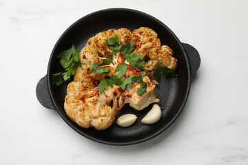 Tasty cauliflower steak in frying pan on white marble table, top view
