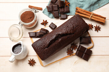 Tasty chocolate sponge cake and ingredients on white wooden table, flat lay