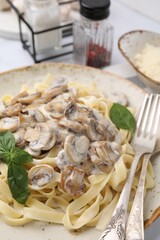 Delicious pasta with mushrooms and basil served on table, closeup