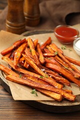 Delicious sweet potato fries with sauces and spices on wooden table, closeup