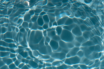 Obraz premium Blue water with ripples on the surface. Defocus blurred transparent blue colored clear calm water surface texture with splashes and bubbles. Water waves with shining pattern texture background.