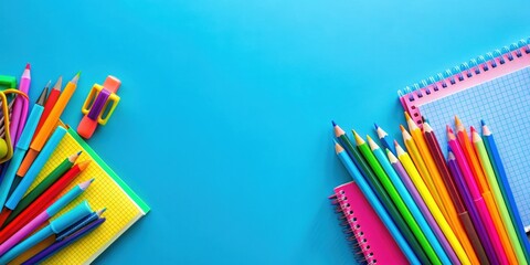 Fototapeta premium Colorful school supplies including notebooks, pencils, and markers on a vibrant blue background, school supplies, colorful