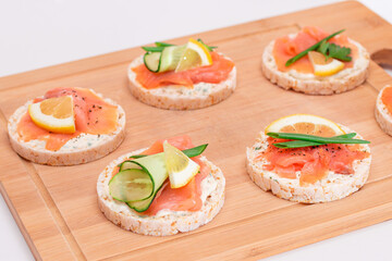 Rice Cake Sandwiches with Fresh Salmon, Cucumber, Lemon and Greens on Bamboo Cutting Board. Diet Food. Quick and Healthy Sandwiches. Crispbread with Fresh Fillings. Healthy Dietary Snacks
