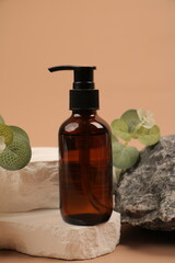 Amber Glass Pump Bottle with Greenery on Natural Stone and Neutral Beige Background