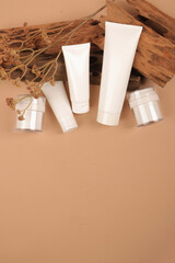 Flat Lay of White Cosmetic Tubes and Jars with Wooden Accents on Beige Background