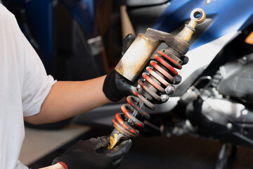 Motorcycle mechanic check and change rear Shock Absorbers motorcycle at motorcycle garage, Damaged Struts and fluid leaks among struts and shocks , repair, maintenance and service concept