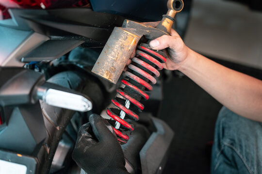 Motorcycle mechanic check and change rear Shock Absorbers motorcycle at motorcycle garage, Damaged Struts and fluid leaks among struts and shocks , repair, maintenance and service concept