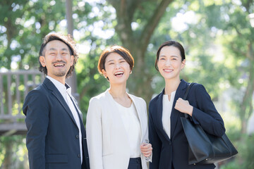 緑の中見上げる男女のビジネス,転職や保険営業マンなどのイメージ　背景は美しい玉ボケの緑のカメラ目線で大笑いの成功のイメージ