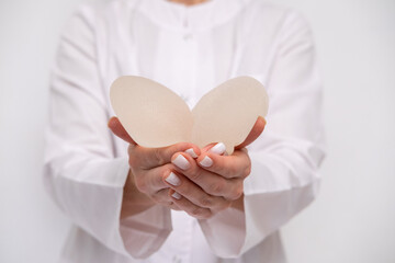 doctor holding breast enlargement implant in hands, heart shape made from implants, plastic...