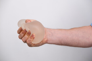 doctor squeezes in his hand breast enlargement implant, plastic surgery, beauty enhancement,...