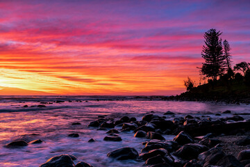 Colourful sunrise sky over ocean rocks at Burleigh. Gold Coast, Australia.