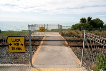 Pedestrian Railway Crossing by Ocean with ‘Look for Trains’ Sign