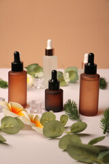 Amber Glass Dropper Bottles with Flowers and Greenery on Neutral Background
